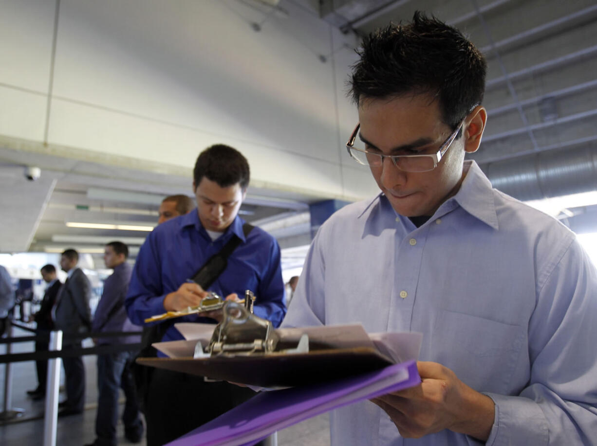 In this Wednesday, Oct. 24, 2012 photo, Fabio Magliano, right, fills out a job application as he stands in line at a job fair in Miami. According to government reports released Friday, Nov. 2, 2012, the U.S. economy added 171,000 jobs in October, and the unemployment rate ticked up to 7.9 percent.