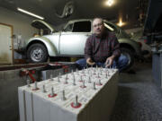 Dean West poses with batteries for the 1974 Volkswagen Super Beetle he has converted to run on all-electrical power in the garage of his home in Milton.