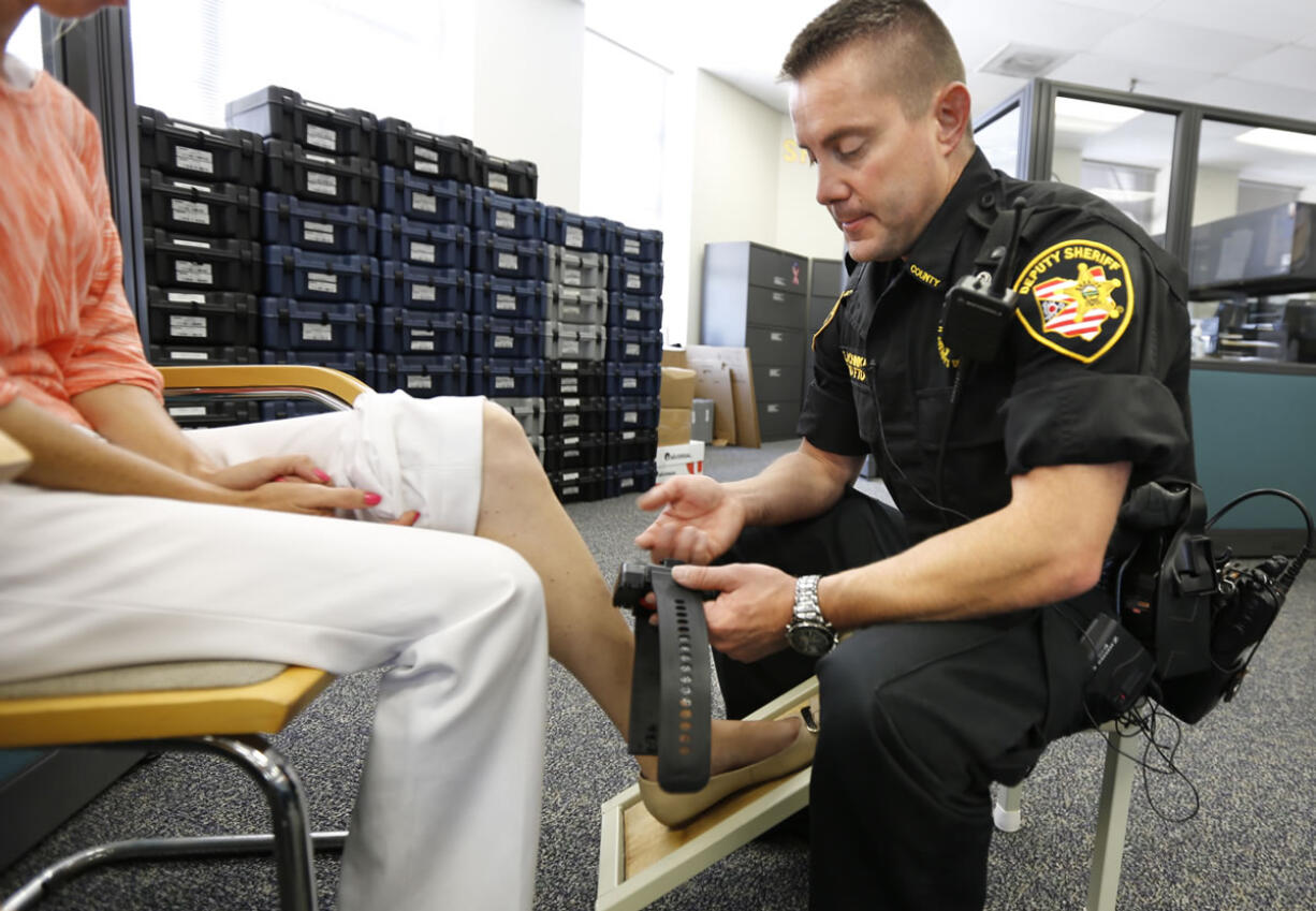 Deputy Edward Schinkal attaches an electronic monitoring unit to a woman who was sentenced to home incarceration last month in Cincinnati.