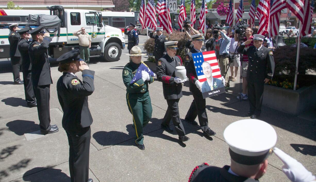 The remains of John Percin Jr. are carried into the Lake Oswego Fire Department Lake Oswego, Ore., where they will lie in state until Friday morning. A public memorial service is scheduled 1 p.m.