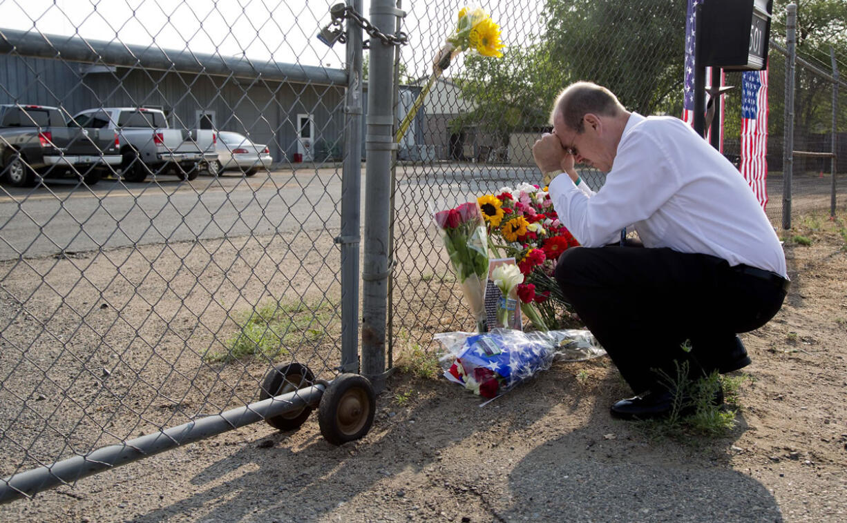 Bob Hoskovec says a prayer as he kneels outside the gate of the Granite Mountain Interagency Hot Shot Crew fire station Monday in Prescott, Ariz.