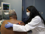 Dr Meeta Khan wears a face mask as she examines a respiratory patient at the Rush University Hospital emergency department, Thursday, Jan. 10, 2013, in Chicago. Flu season in the U.S. has hit early and, in some places, hard. But whether this will be considered a bad season by the time it has run its course in the spring remains to be seen.