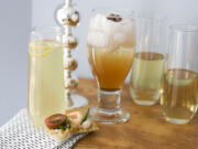 A glass of citrus bubbly with a small curl of lemon on top, from left, a glass of spiced rose-pomegranate spritzer with a star anise on top, and two glasses of sparkling wine, with canapes are shown on a table in Concord, N.H.