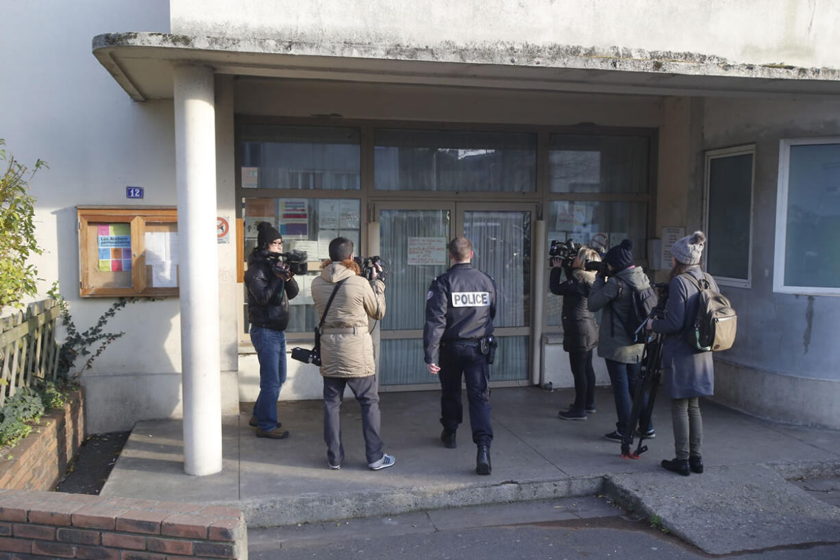 A police enters a pre-school Monday in Paris suburb Aubervilliers. French anti-terrorism authorities are investigating an attack Monday on a preschool teacher in a Paris suburb by a masked assailant with a box-cutter and scissors who invoked the Islamic State group.