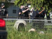 Police officers move in, weapons drawn and deploying a shield, to secure a shooting scene enough to allow medics to treat a man who'd been shot in the yard of a home in the Fruit Valley neighborhood.