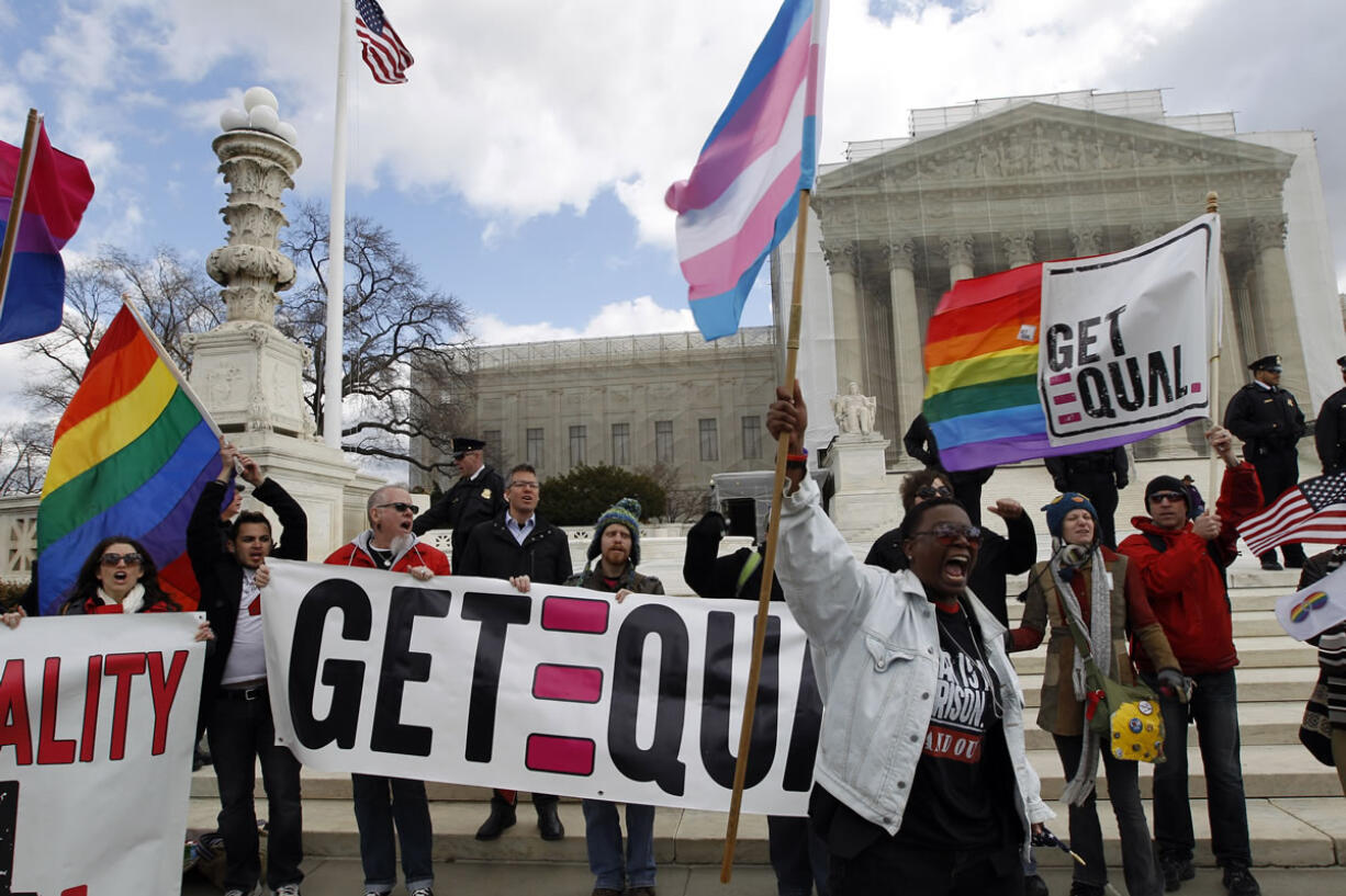 Jose Luis Magan/Associated Press files
Demonstrators hold flags and chant in front of the U.S. Supreme Court in Washington on March 27, the second day of gay marriage cases before the court. The Supreme Court's landmark ruling on same-sex marriage has private employers around the country scrambling to make sure their employee benefit plans comply with the law.