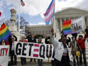 Jose Luis Magan/Associated Press files
Demonstrators hold flags and chant in front of the U.S. Supreme Court in Washington on March 27, the second day of gay marriage cases before the court. The Supreme Court's landmark ruling on same-sex marriage has private employers around the country scrambling to make sure their employee benefit plans comply with the law.