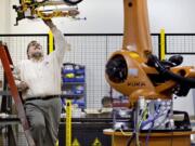 In this Jan. 15, 2013, photo, Rosser Pryor, Co-owner and President of Factory Automation Systems, examines a new high-performance industrial robot at the company's Atlanta facility. Pryor, who cut 40 of 100 workers since the recession, says while the company is making more money now and could hire ten people, it is holding back in favor of investing in automation and software.