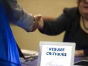 A job seeker stops at a table offering resume critiques during a job fair in Atlanta.