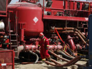 In 2009, an unidentified worker steps through a maze of hoses being used at a remote fracking site being run by Halliburton for natural gas producer Williams in Rulison, Colo.