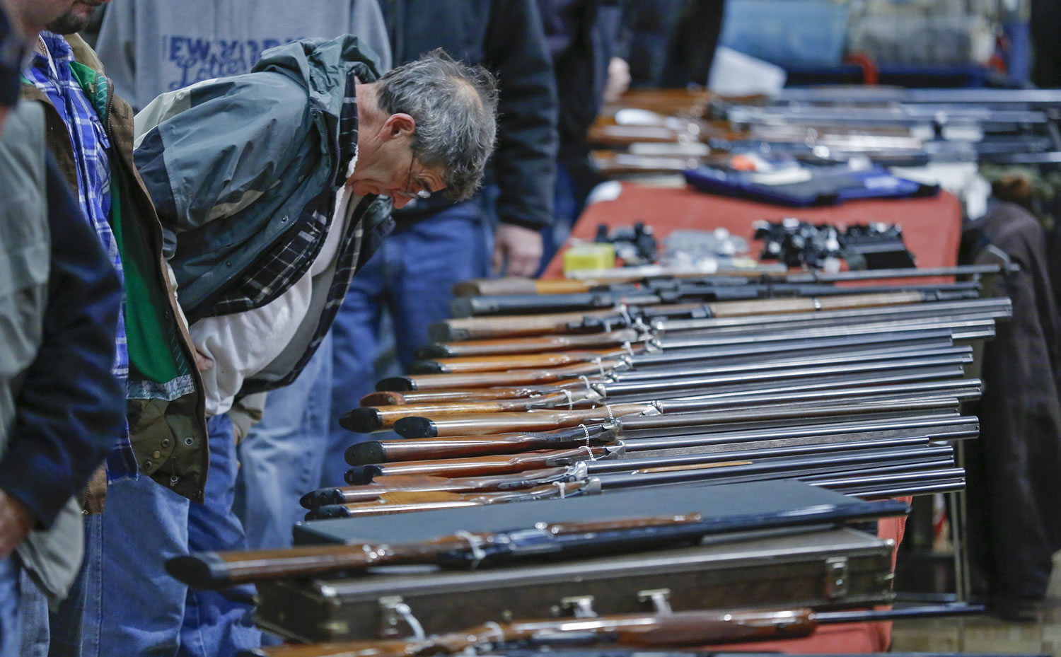 A customer looks over shotguns on display at the annual New York State Arms Collectors Association Albany Gun Show at the Empire State Plaza Convention Center in Albany, N.Y.