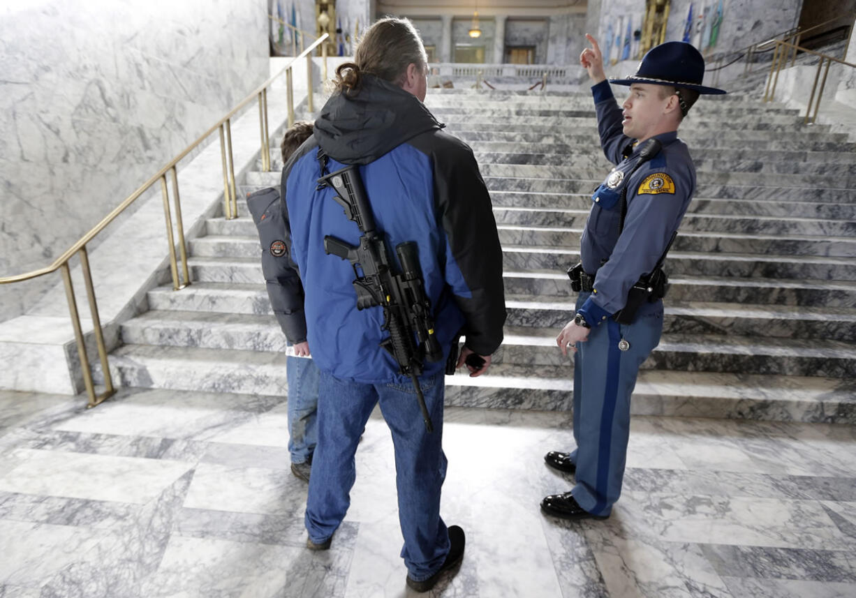 Wearing an AR-15 rifle, Tim Hanrahen, left, of Snohomish, Wash., gets information on the location of legislative offices from Washington State Patrol trooper Todd Israel, right, after Hanrahen attended a gun rights rally Friday at the Capitol in Olympia.