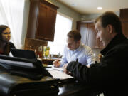 Insurance broker Jeff Lindstrom, right, meets with Brandi and Darren Litchfield to discuss health insurance plan options, at their home in the Seattle suburb of Bothell.