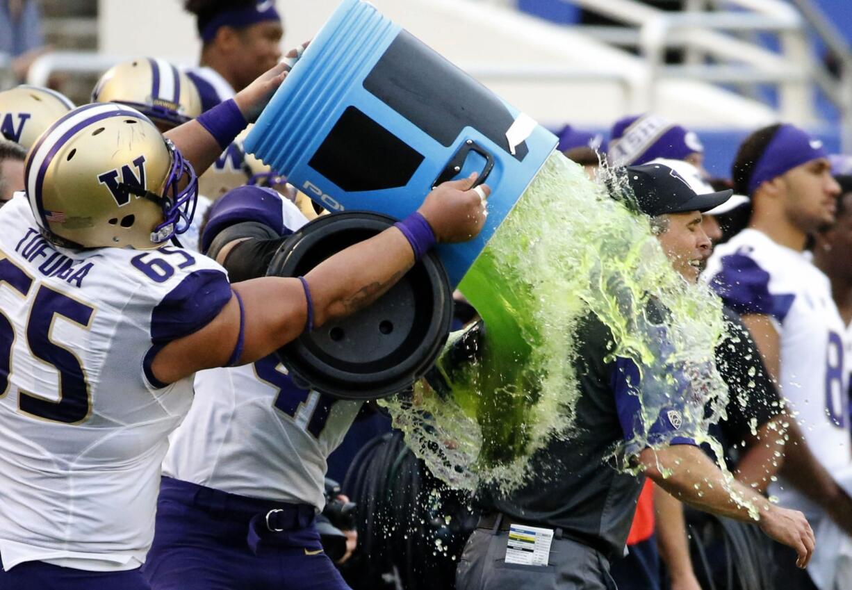 Washington offensive lineman Siosifa Tufunga (65) pours sport drink on head coach Chris Petersen just after  Washington's 44-31victory over Southern Mississippi at the Heart of Dallas Bowl NCAA college football game, Saturday, Dec. 26, 2015, in Dallas.