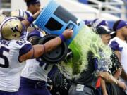 Washington offensive lineman Siosifa Tufunga (65) pours sport drink on head coach Chris Petersen just after  Washington's 44-31victory over Southern Mississippi at the Heart of Dallas Bowl NCAA college football game, Saturday, Dec. 26, 2015, in Dallas.