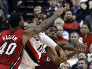 Portland Trail Blazers forward LaMarcus Aldridge, middle, is wrapped up by Miami Heats'  LeBron James, right, and Udonis Haslem during the second half of an NBA basketball game in Portland, Ore., Thursday, Jan. 10, 2013.