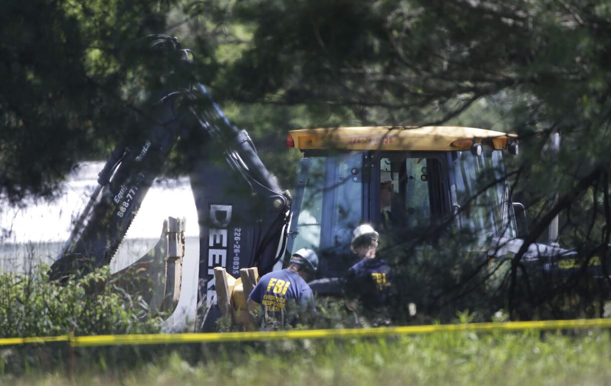 Members of an FBI evidence response team look over an area being cleared in Oakland Township, Mich., on Tuesday where officials continue the search for the remains of Teamsters union president Jimmy Hoffa, who disappeared from a Detroit-area restaurant in 1975.