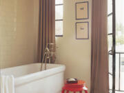 A neutral master bath is brightened with a vintage, Chinese burnt orange garden stool.