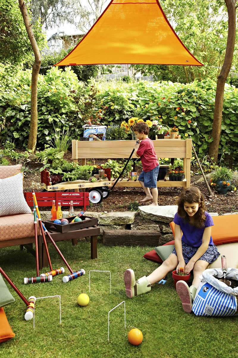 Designer Brian Patrick Flynn for Hayneedle.com made this Los Angeles backyard a bit more kid-friendly by covering a portion of it with a bold orange shade sail which is suspended with turnbuckles and rope to three nearby trees.