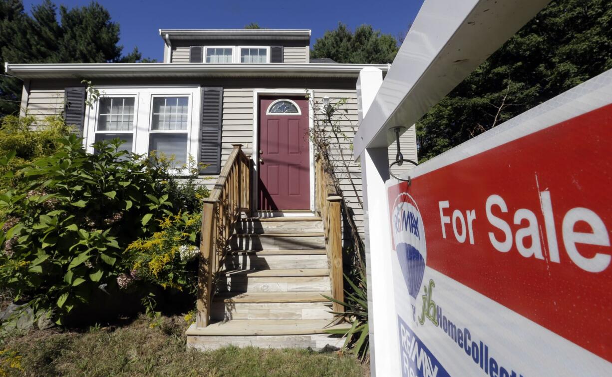 A for sale sign hangs in front of a house in Walpole, Mass.