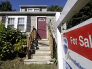 A for sale sign hangs in front of a house in Walpole, Mass.