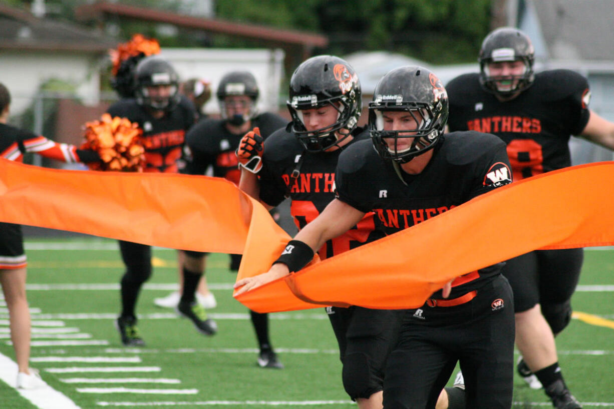 The Washougal High School football players break the ticker tape on their new field turf Friday, at Fishback Stadium.