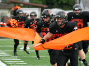 The Washougal High School football players break the ticker tape on their new field turf Friday, at Fishback Stadium.