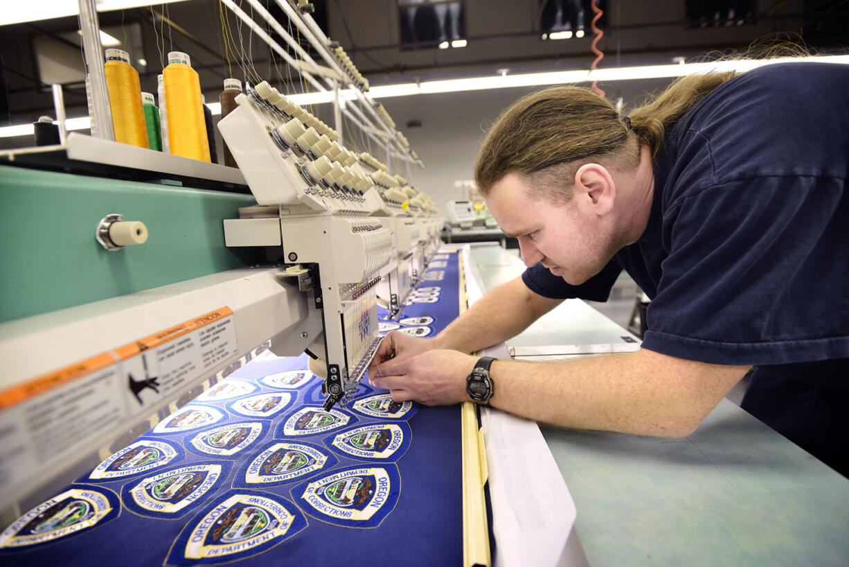 Inmate Leroy Savelesky rethreads a needle on a six headed embroidery machine Jan. 17 at the Eastern Oregon Correctional Institution garment factory in Pendleton, Ore.