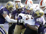 Four Washington defenders wrap up Idaho State's Xavier Finney in the first half Saturday at Husky Stadium.