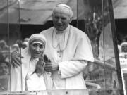 Pope John Paul II holds his arm around Mother Teresa in February 1986 as they ride in the Popemobile outside the Home of the Dying in Kolkata, India. Mother Teresa, the tiny stooped nun who cared for the poorest of the poor in the slums of India and beyond, will be declared a saint next year after Pope Francis approved a miracle attributed to her intercession.