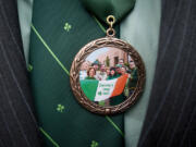 As seen in a medallions's reflection, family and friends of the late Denny Lane raise the Irish flag in his honor on St. Patrick's Day 2011 at the Clark County Courthouse.