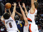 Meyers Leonard, right, puts up a defensive blockade with Adam Morrison, left, and Joel Freeland against Utah Jazz's DeMarre Carroll.