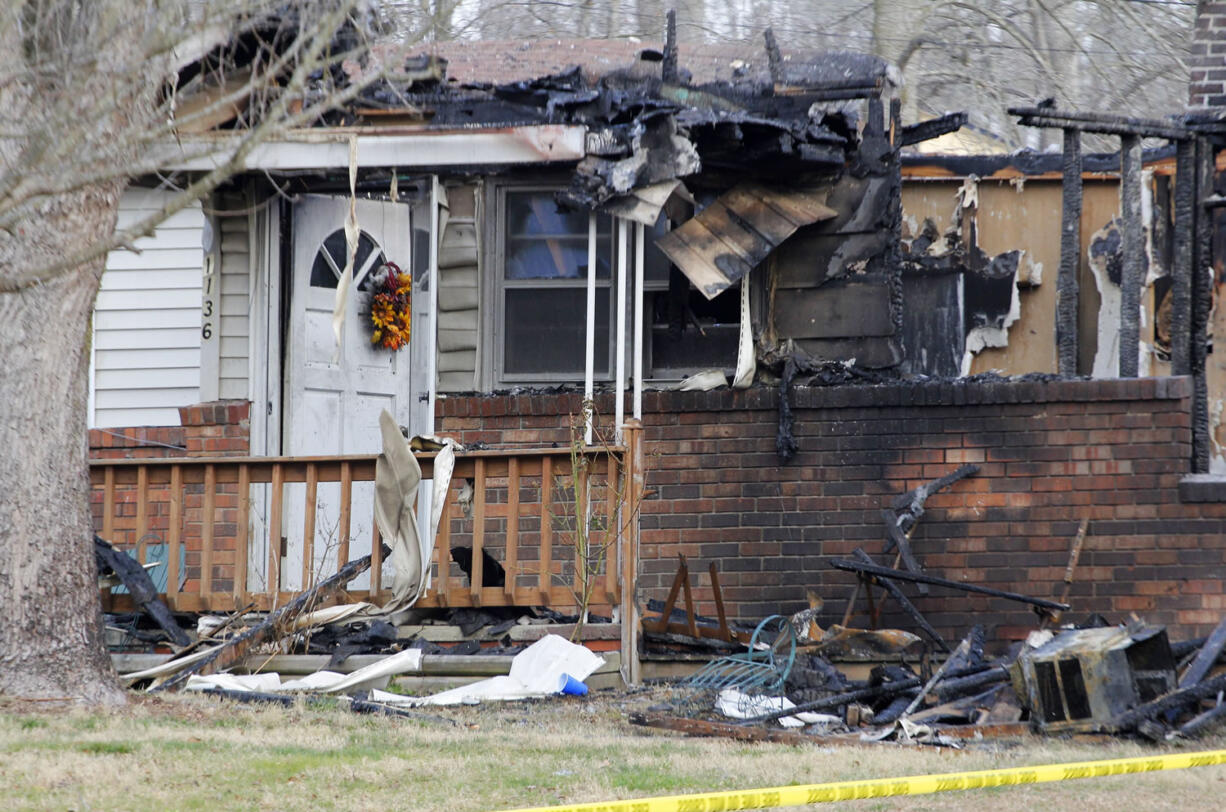 The charred remains of a home stand empty after a fire erupted Friday in Gray, Ky., killing two adults and five children inside.