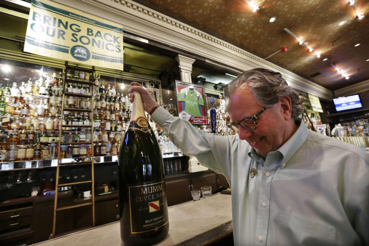 Bar owner Mick McHugh grimaces as he grips a a bottle of Champagne he intends to open when Seattle gets an NBA basketball team, after hearing rumors before an official announcement that the Sacramento Kings would not be sold to Seattle investors, Wednesday, May 15, 2013 in Seattle. NBA owners voted Wednesday to reject the Sacramento Kings' proposed move to Seattle, the latest in a long line of cities that have tried to land the franchise. The vote followed a recommendation made last month by the NBA's relocation committee and may have finally brought an end to an emotional saga that has dragged on for nearly three years.