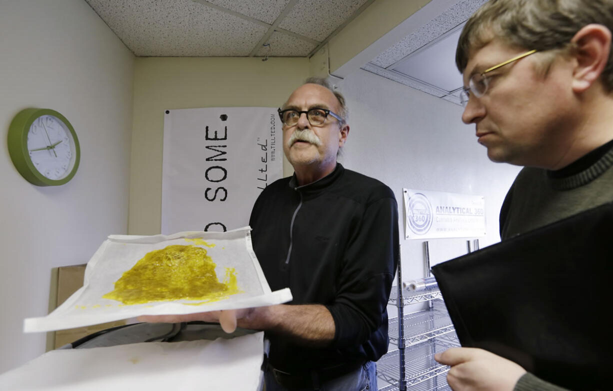 Jim Andersen, left, shows butane hash oil to Mike Steenhout, comptroller of Washington's Liquor Control Board, at a marijuana-growing facility April 4 in Seattle.