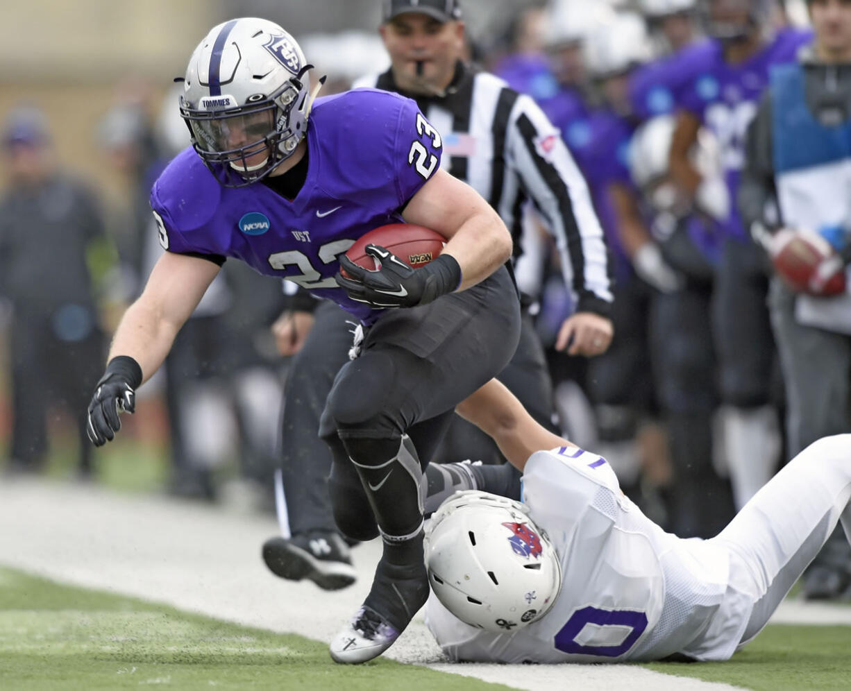 Linfield middle linebacker Skylor Elgarico (10) pulls St. Thomas running back Jordan Roberts (23) out of bounds during the first quarter during a Division III NCAA college football semifinal game on Saturday, Dec. 12, 2015, in St. Paul, Minn.