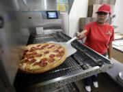 Employee Rosy Tirado pulls a pepperoni pizza from an oven at a Pizza Patron in Dallas, Texas.