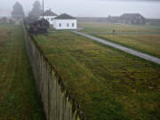 A visitor walking through Fort Vancouver National Historic Site is observed from an upper story of the bastion at the northwest corner of the reconstructed stockade.