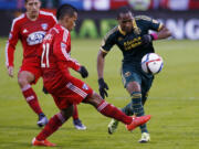 FC Dallas midfielder Michael Barrios (21) chips the ballast Portland Timbers midfielder Darlington Nagbe, right, during the first half of  the MLS soccer Western Conference championship match, Sunday, Nov. 29, 2015, in Frisco, Texas. The teams tied 2-2, but Portland advanced on aggregate score.