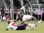 New England Revolution midfielder Kalifa Cisse, left, slides in to steal the ball from Portland Timbers forward Rodney Wallace during the first half Thursday.