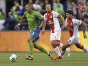 Seattle Sounders' Clint Dempsey dribbles the ball as Portland Timbers' Jack Jewsbury (13) and Diego Valeri (8) defend in the first half Sunday in Seattle.