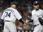 Mariners starting pitcher Felix Hernandez (34) reacts to a play by second baseman Dustin Ackley, right, for an out on Houston's Carlos Pena.