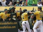 Oakland Athletics' Josh Reddick (16) and Coco Crisp (4) celebrate after Crisp scored against the Seattle Mariners in the eighth inning Thursday.