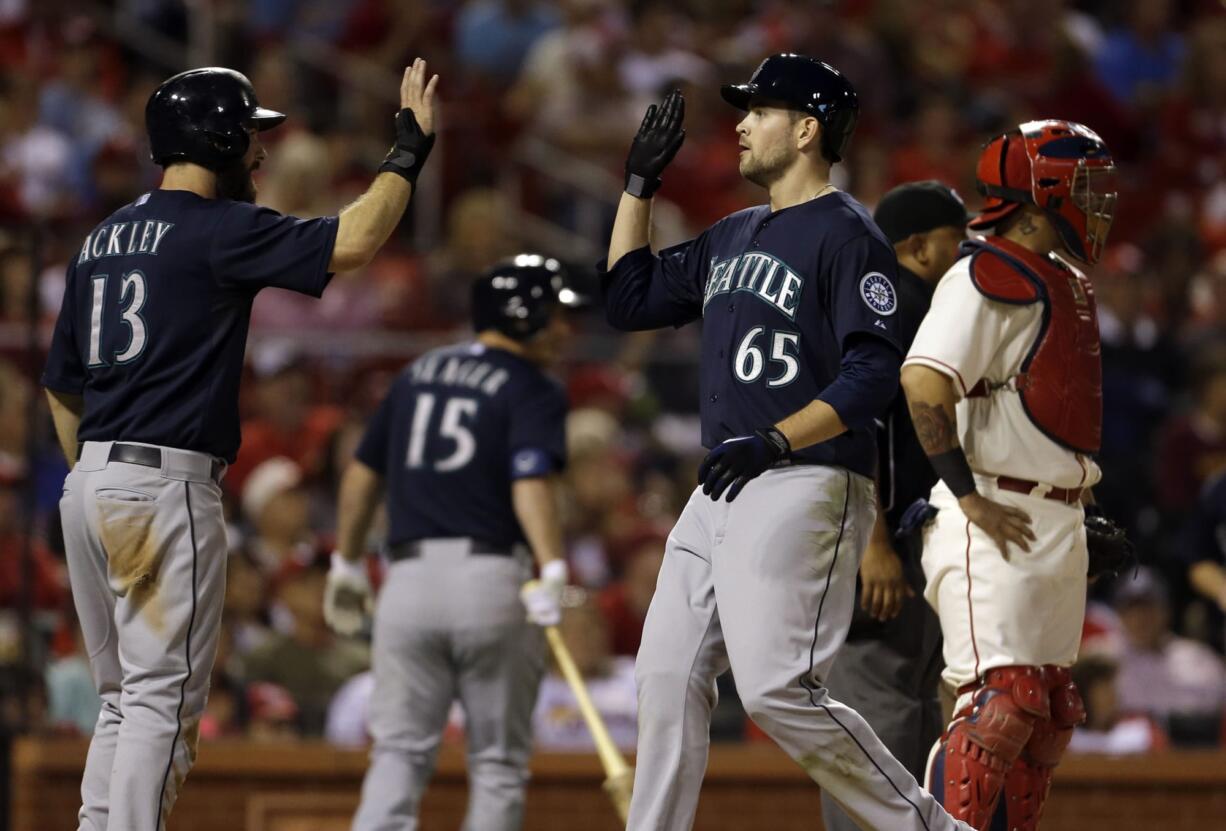 Seattle Mariners' Dustin Ackley (13) and James Paxton (65) celebrate after scoring on a two-run double by Franklin Gutierrez as St.