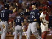 Seattle Mariners' Dustin Ackley (13) and James Paxton (65) celebrate after scoring on a two-run double by Franklin Gutierrez as St.