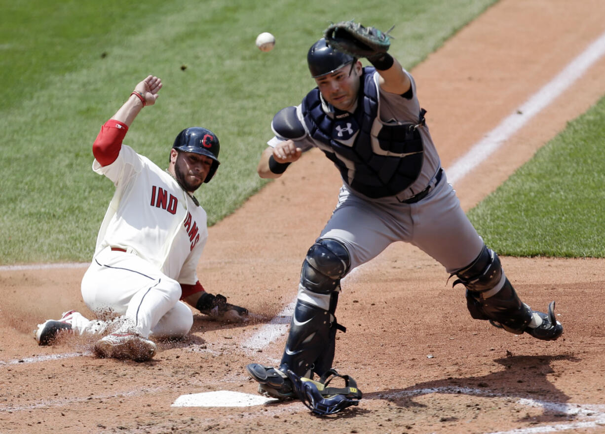 Cleveland Indians' Mike Aviles slides into home for a run to make the score 6-0 in the fourth inning Sunday as Seattle Mariners catcher Jesus Montero cannot hold on to the ball.