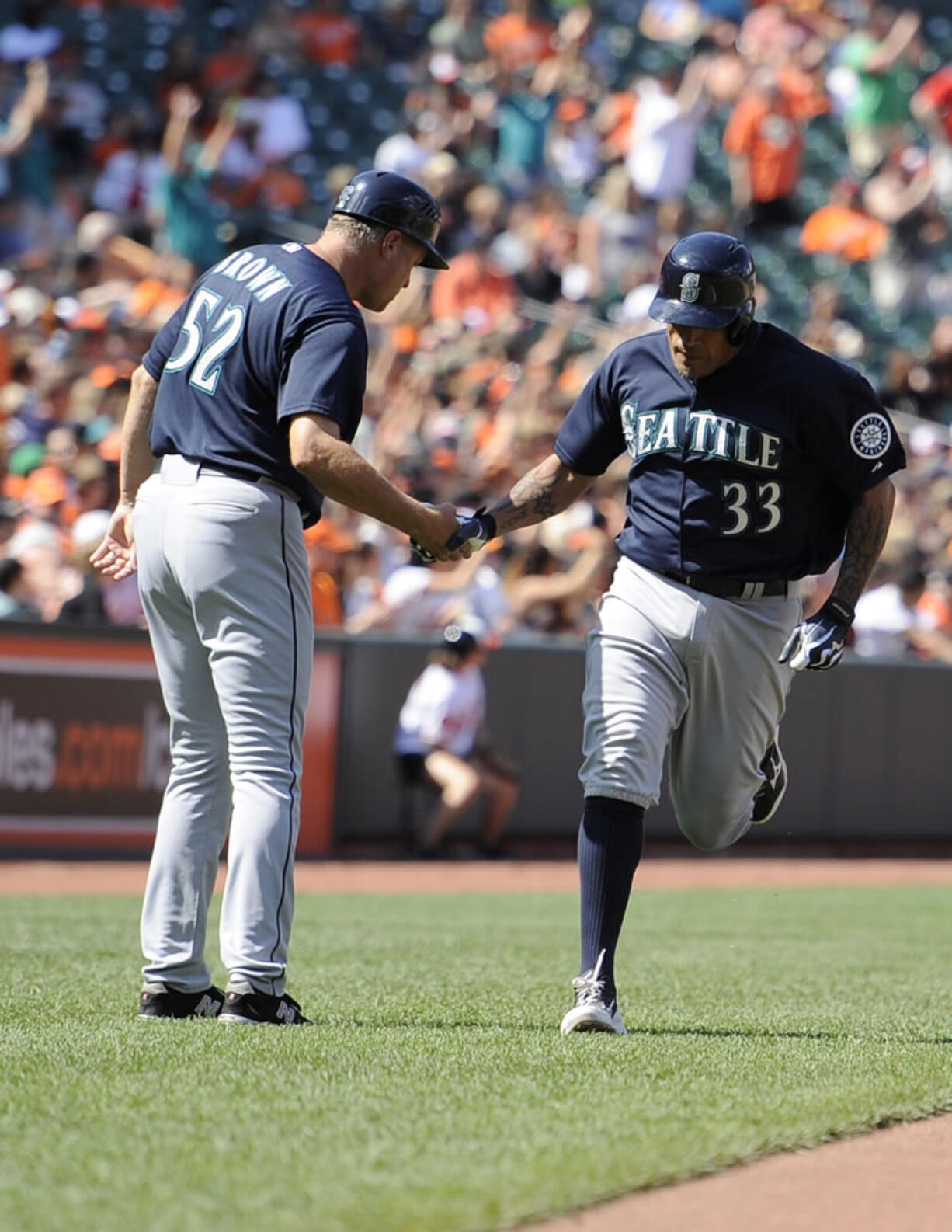 Seattle Mariners' Henry Blanco (33) is greeted by third base coach Daren Brown (52) after his two-run home run against the Baltimore Orioles during the seventh inning Sunday.