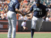 Seattle Mariners' Henry Blanco (33) is greeted by third base coach Daren Brown (52) after his two-run home run against the Baltimore Orioles during the seventh inning Sunday.