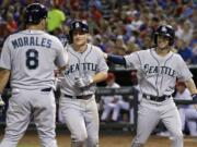 Seattle Mariners' Kendrys Morales (8) and Nick Franklin, right, congratulate Kyle Seager, center, at the plate following Seager's two-run home run off Texas Rangers relief pitcher Neal Cotts that scored Franklin in the eighth inning of a baseball game, Friday, Aug. 16, 2013, in Arlington, Texas.