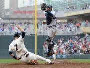 Joe Mauer (7) scores the game-winning run as  Mariners catcher Kelly Shoppach jumps to reach the throw.